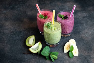 Renkli meyve suyu, ahududu, kivi, muz ve yabanmersinli taze vitaminler. Sağlıklı detoks vitamin diyeti ya da arka planda vegan gıda konsepti.