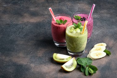 Renkli meyve suyu, ahududu, kivi, muz ve yabanmersinli taze vitaminler. Sağlıklı detoks vitamin diyeti ya da arka planda vegan gıda konsepti.