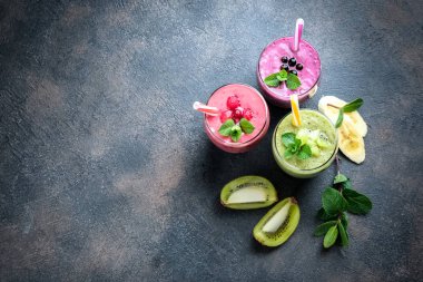 Renkli meyve suyu, ahududu, kivi, muz ve yabanmersinli taze vitaminler. Sağlıklı detoks vitamin diyeti ya da arka planda vegan gıda konsepti, fotokopi alanı olan üst görünüm.