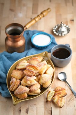 Seramik kasede süzme peynirli ev yapımı kurabiyeler ve ahşap arka planda bakır kahve.