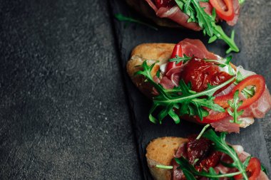 Geleneksel İtalyan bruschetta, domatesli, jambonlu, krem peynirli ve roka arkaplanlı. Kopyalama alanı olan üst görünüm