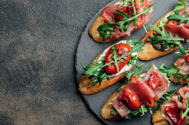 Geleneksel İtalyan bruschetta, domatesli, jambonlu, krem peynirli ve roka arkaplanlı. Kopyalama alanı olan üst görünüm