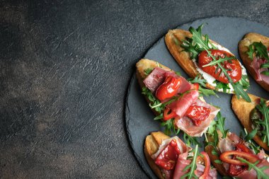Geleneksel İtalyan bruschetta, domatesli, jambonlu, krem peynirli ve roka arkaplanlı. Kopyalama alanı olan üst görünüm