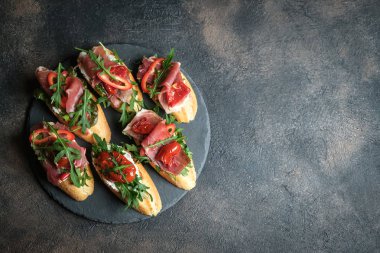 Geleneksel İtalyan bruschetta, domatesli, jambonlu, krem peynirli ve roka arkaplanlı. Kopyalama alanı olan üst görünüm