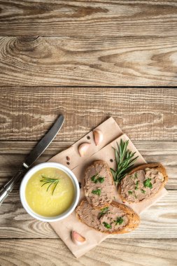 Seramik kasede taze ev yapımı tavuk ciğeri ezmesi ya da ramekin ve baget dilimleri otlu börek ve ahşap arka planda sarımsak. Üst görünüm.