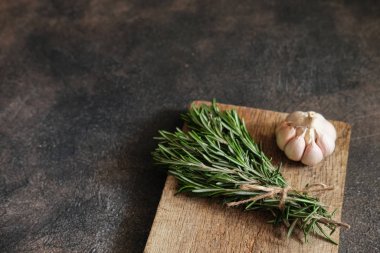 Siyah bir arka planda bir demet taze biberiye ve sarımsak..