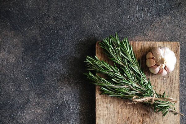 Bunch of fresh rosemary and garlic on a black background.Top view with copy space.