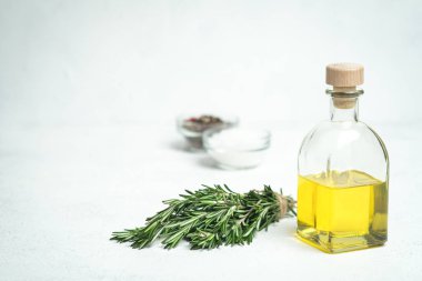 Bir demet taze biberiye, sarımsak ve zeytinyağlı şişe arka planda..