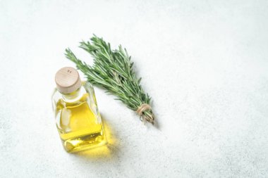 Bir demet taze biberiye, sarımsak ve zeytinyağlı şişe arka planda..