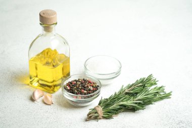 Bir demet taze biberiye, sarımsak ve zeytinyağlı şişe arka planda..