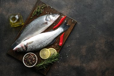 Taze deniz kabuğu ve pişirmek için malzemeler. Çiğ balık deniz kabuğu, limon, baharat ve otlar siyah ahşap kırsal masada. Kopyalama alanı olan üst görünüm.
