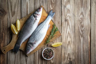 Taze deniz kabuğu ve pişirmek için malzemeler. Çiğ balık deniz kabuğu, limon, baharat ve otlar ahşap kırsal masada. Kopyalama alanı olan üst görünüm.