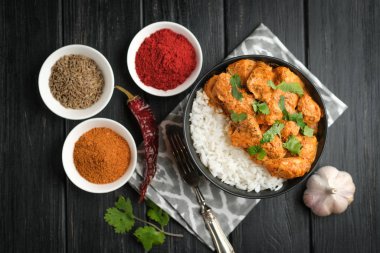 Geleneksel Asya usulü tavuk tikka masala pirinç domatesli baharatlı et yemeği ve siyah bir kasede kişniş..