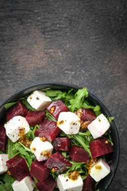 Pancar salatası, beyaz peynir, roka ve koyu arkaplanda baharatlı sos. Sağlıklı yiyecekler. Üst Manzara. Boşluğu kopyala.