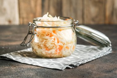 Kırsal bir zeminde cam kavanozda baharatlı ev yapımı lahana turşusu. Fermente edilmiş ürün.