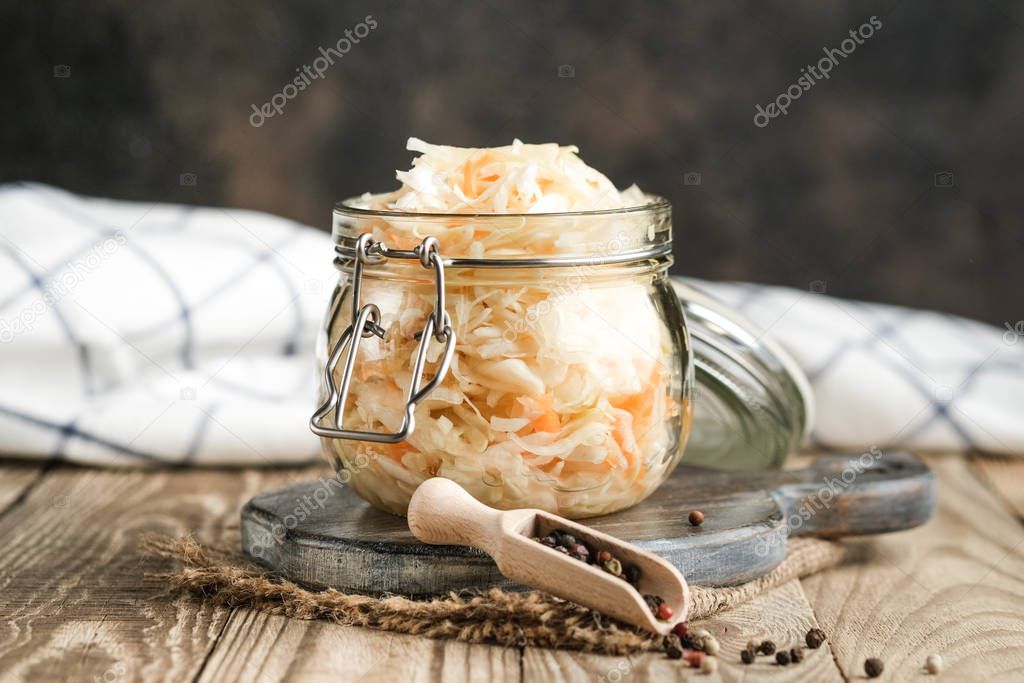 Homemade sauerkraut with spices in a glass jar on a rustic background. Fermented product.