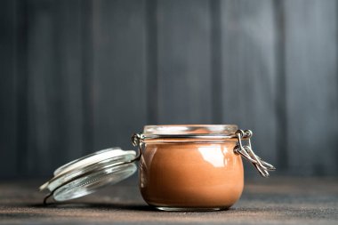 Çilekli cam kavanozda çikolatalı mus ve arka planda kırsal bir fotokopi alanı. Ev yapımı tatlı..