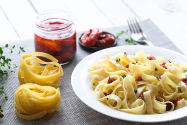 Kurutulmuş domatesli İtalyan geleneksel makarna tagliatelle ve arka planda kekik..