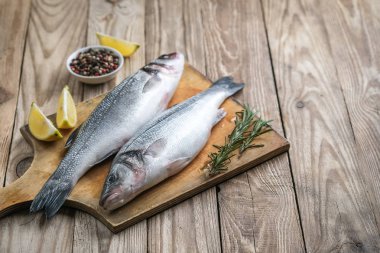 Taze deniz kabuğu ve pişirmek için malzemeler. Çiğ balık deniz kabuğu, limon, baharat ve otlar ahşap kırsal masada. Kopyalama alanı olan üst görünüm.