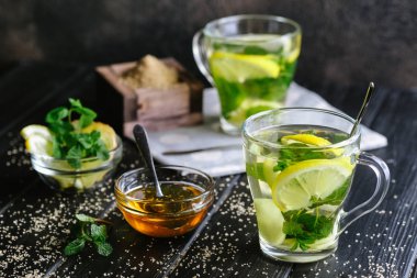 Limon dilimli taze zencefil çayı, koyu arkaplanda nane ve bal..