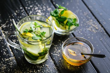 Limon dilimli taze zencefil çayı, koyu arkaplanda nane ve bal..