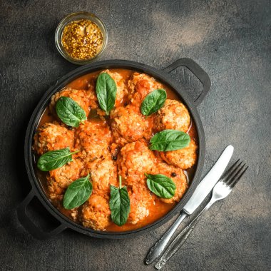 Koyu arkaplanda fesleğen yaprağıyla domates soslu köfte. Üst görünüm.