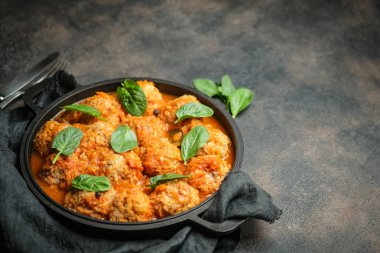 Koyu arkaplanda fesleğen yaprağıyla domates soslu köfte. Üst görünüm.