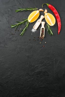 Selection of spices, herbs and lemon. Ingredients for cooking. Food background on dark stone table. Top view copy space