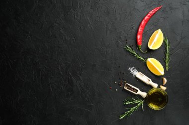 Selection of spices, herbs and lemon. Ingredients for cooking. Food background on dark stone table. Top view copy space