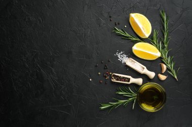 Selection of spices, herbs and lemon. Ingredients for cooking. Food background on dark stone table. Top view copy space