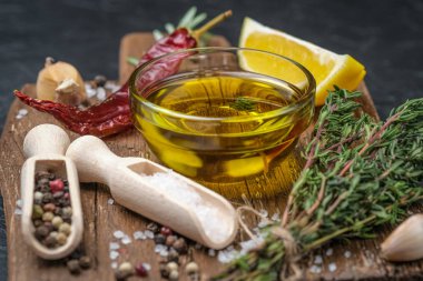 Selected ingredients for cooking. Lemon, herbs, olive oil and spices on a cutting board on a dark stone background.  Top view copy space.