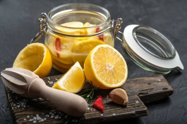 Salted lemons in glass jar with ingredients on a dark background. Moroccan cuisine.