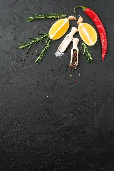 Selection of spices, herbs and lemon. Ingredients for cooking. Food background on dark stone table. Top view copy space