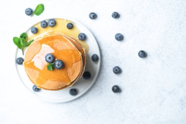 Pancakes with berries and honey on a light rustic background copy space. Very hearty tasty breakfast. Top view.