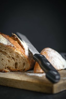 Ekmek. Ev yapımı kepekli ekmeği kesme tahtasının üzerinde siyah arka plan fotokopi alanındaki bir bıçakla dilimledim..