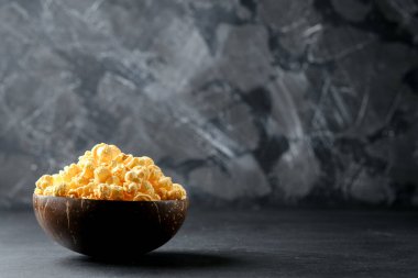 Hindistan cevizi kasesindeki peynirli patlamış mısır. Arka planda koyu bir kopya alanı var..