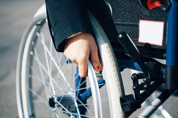 Tekerlekli sandalye tutan bir kadın eli, engelli hayatı.