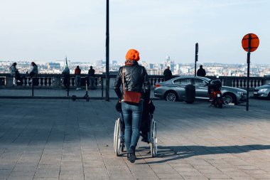 Arka planda, tekerlekli sandalyeyi iten bir kadının, arka planda metropol şehri olan bir hastayla birlikte oturduğu görüntüler. Sağlık ve sakatlık konsepti.