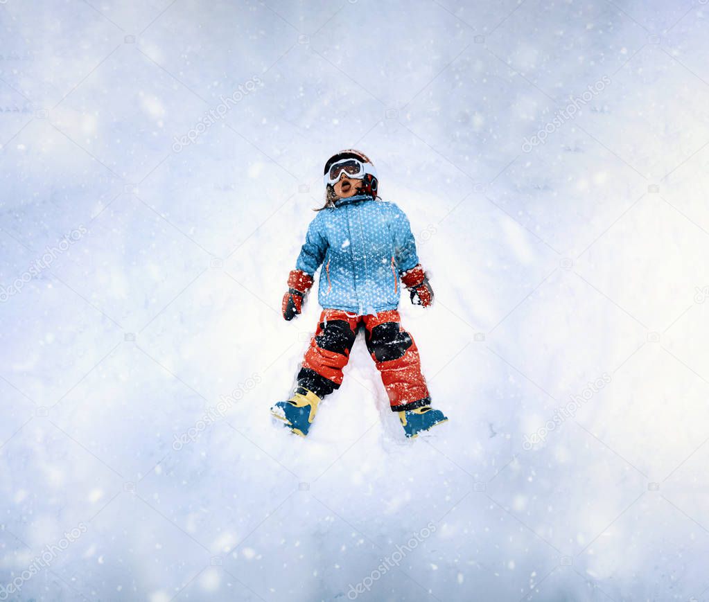 top view of a little girl dressing ski wear lying down and savoring the snow while it snows