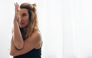 Çapraz ellerle yoga pozisyonu alan beyaz bir kadının portresi. Denge ve odaklanma egzersizi.