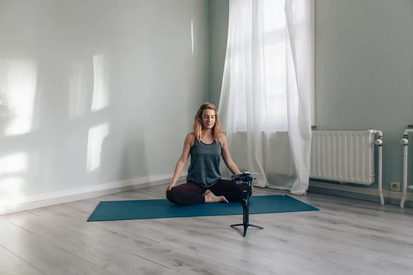 Jeune femme blogueuse enregistrement elle-même faire du yoga à l'aide d'un téléphone avec gimbal - concept star des médias sociaux — Photo
