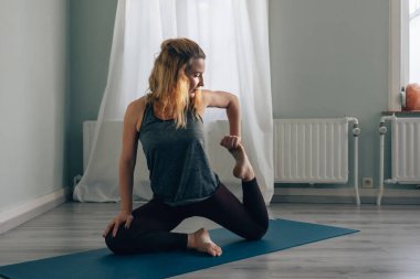 Genç, rahat ve düşünceli kadın içeride yoga yapıyor.