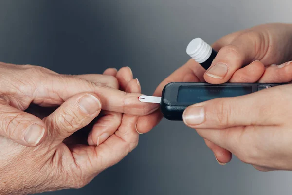 Bir kadın diyabetik hastada glikoz değerlerini test eden bir bebek odasının ellerine yakın çekim - hipoglisemi yeni tıbbi cihazlar konsepti