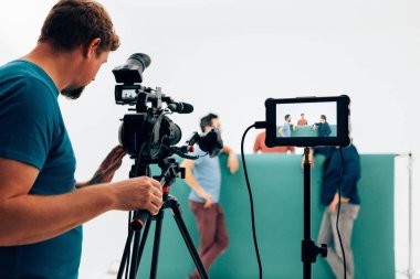 Profesyonel kamera operatörü stüdyoda üç aktörle video çekiyor.