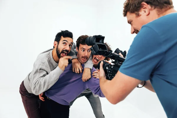 three people acting in front of the camera in a white studio background