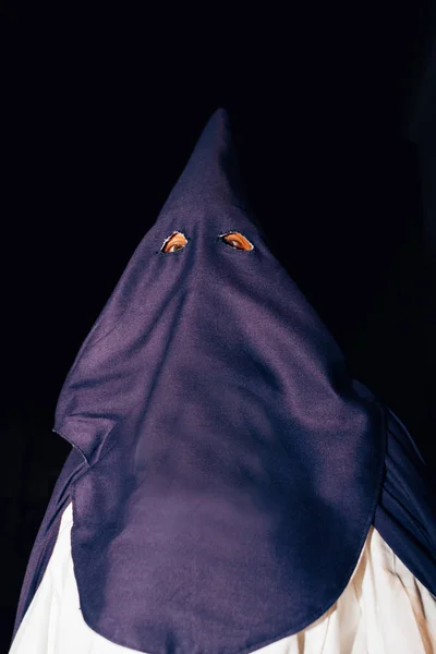 hooded man during a Christian religious procession at night