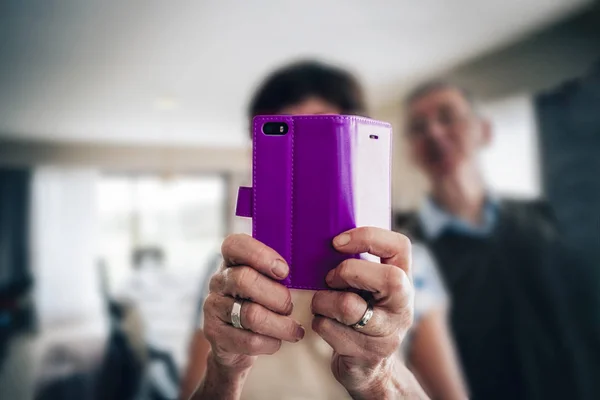 Yaşlılar ve teknoloji kavramı - cep telefonu kullanarak fotoğraf çeken yaşlı bir kadının ellerinde.