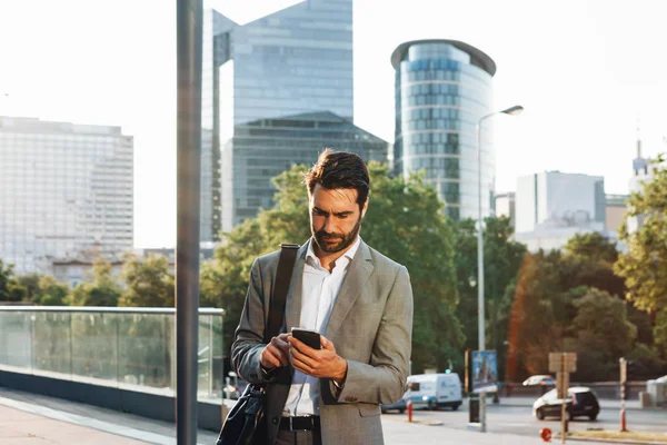 Şehir merkezindeki finans bölgesinde akıllı telefonuna bakan şehir işadamı yakışıklı 30 'lu yaşlarda erkek. Ofis dışındaki caddede e-postaları kontrol ediyor ve mesajlaşıyor. 
