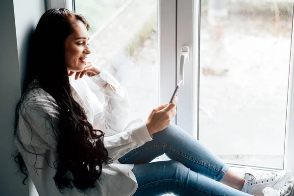 Attractive Young Smiling Woman Sitting Windowsill Using Mobile Phone — Stock Photo, Image