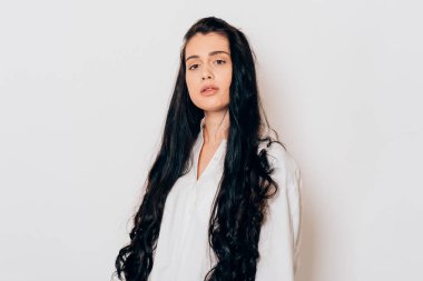 Beyaz arka planda uzun siyah saçlı, şehvetli bir genç kadının portresi. 